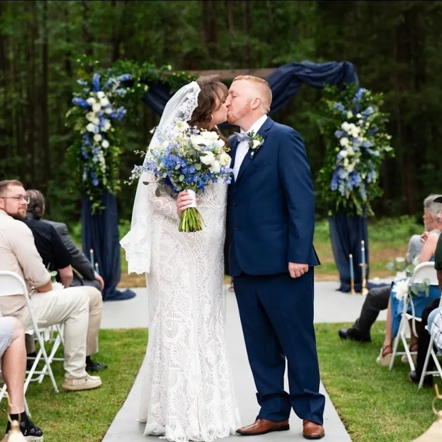Chateau Amelia - Bride and groom kissing at outdoor wedding ceremony at charming wedding venue setting