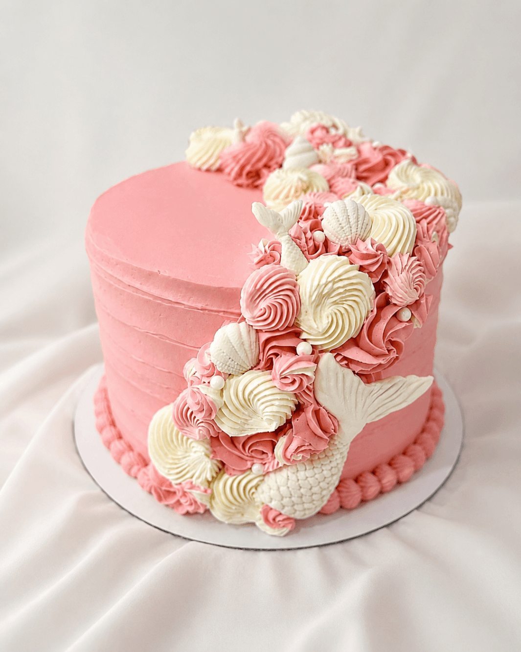 Spilled Milk Cake Boutique - Blush buttercream celebration cake with seashell-inspired piping and sculpted mermaid tail details